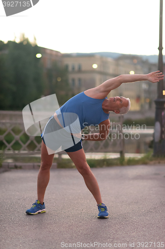 Image of handsome man stretching before jogging