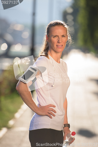 Image of woman drinking  water after  jogging