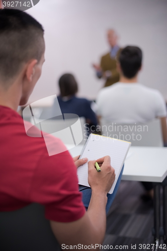 Image of male student taking notes in classroom