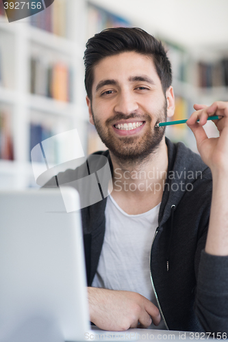 Image of student in school library using laptop for research