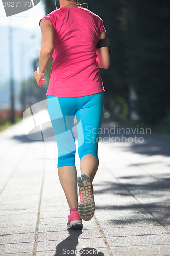 Image of sporty woman running  on sidewalk
