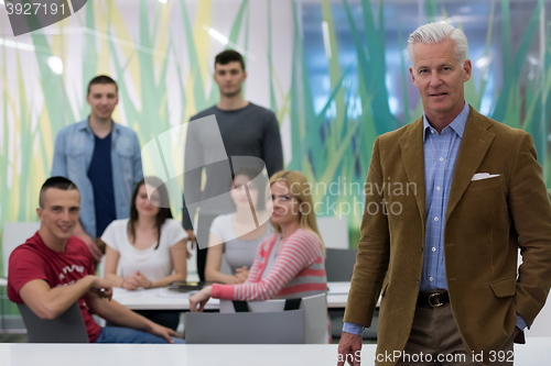 Image of portrait of  teacher with students group in background