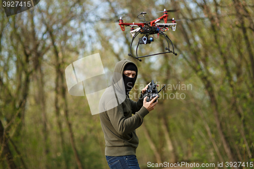 Image of Man in mask operating a drone with remote control.