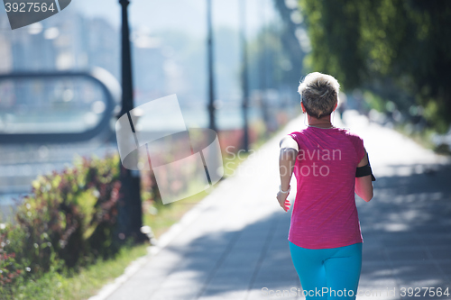 Image of sporty woman running  on sidewalk