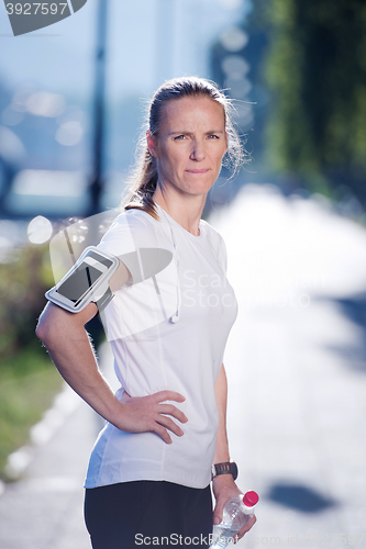 Image of woman drinking  water after  jogging