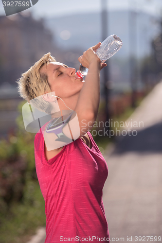 Image of woman drinking  water after  jogging