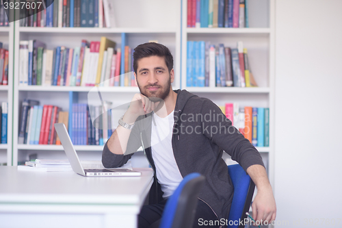 Image of student in school library using laptop for research