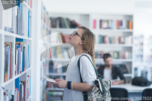 Image of famale student selecting book to read in library