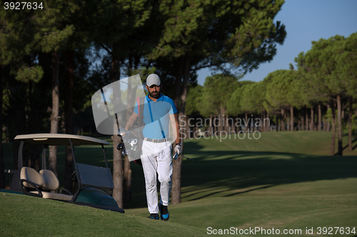 Image of golfer  walking and carrying golf  bag