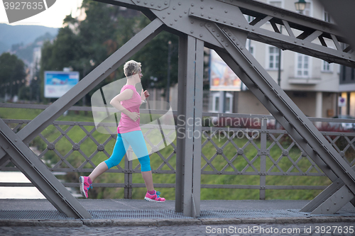Image of sporty woman running  on sidewalk