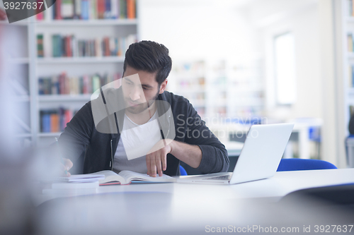 Image of student in school library using laptop for research