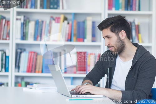 Image of student in school library using laptop for research