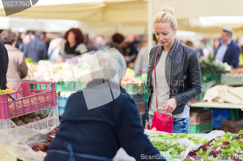 Image of Woman buying vegetable at local food market. 