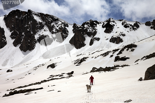 Image of Hiker and dog in snowy mountains at spring