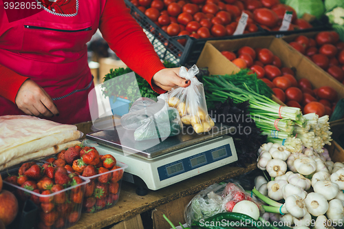 Image of the seller is weighing vegetables on scales