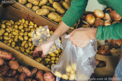 Image of woman puts a package of new potatoes on the market