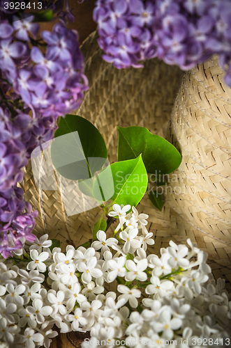 Image of Still-life with a bouquet of lilacs and a straw hat, close-up