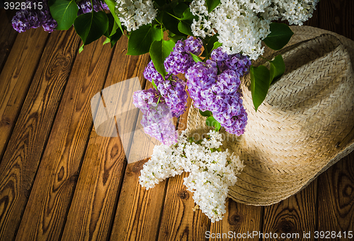 Image of Still-life with a bouquet of lilacs and a straw hat, close-up