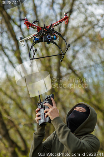 Image of Man in mask operating a drone with remote control.