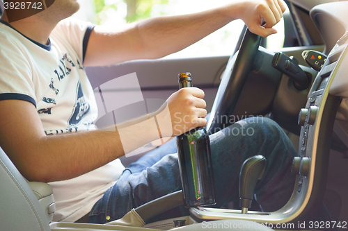 Image of Man drinking beer while driving the car.