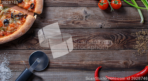 Image of Tasty pizza with ingridients on a wooden board.