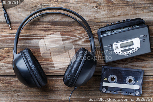 Image of Headphones, player and retro compact cassette over wooden background. Top view