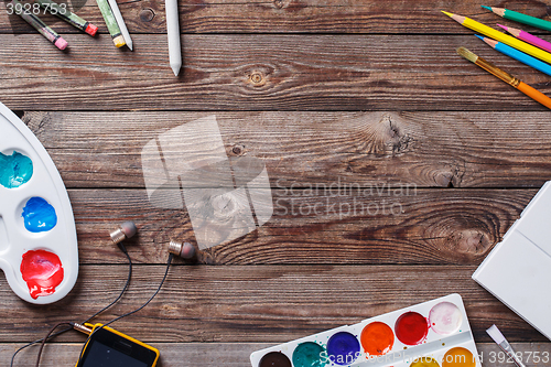 Image of Paper, watercolors, paint brush and some art stuff on wooden   table