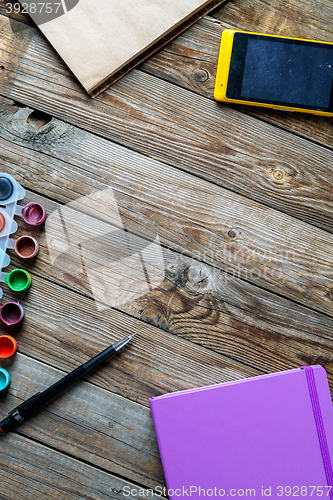 Image of Watercolors, color pencils and sketchbook on wooden table. Flat lay photo with empty space for logo, text.