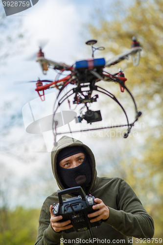 Image of Man in mask operating a drone with remote control.