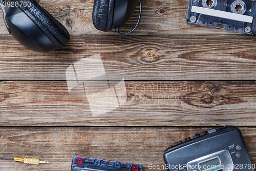 Image of Cassette tapes, cassette player and headphones over wooden table. top view.