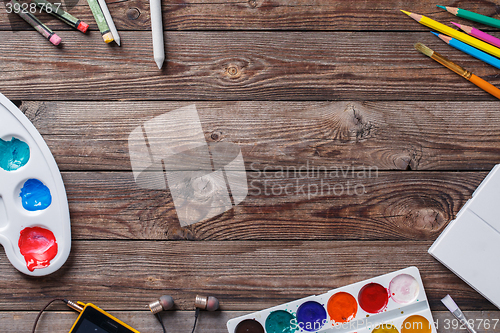 Image of Paper, watercolors, paint brush and some art stuff on wooden   table