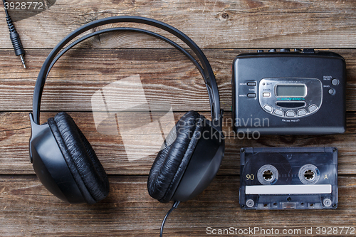 Image of Headphones, player and retro compact cassette over wooden background. Top view
