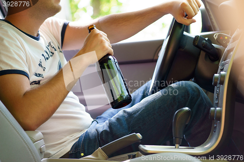 Image of Man drinking beer while driving the car.