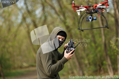 Image of Man in mask operating a drone with remote control.