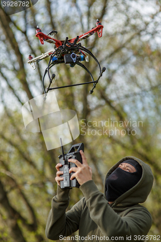 Image of Man in mask operating a drone with remote control.