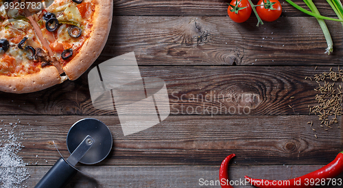 Image of Tasty pizza with ingridients on a wooden board.