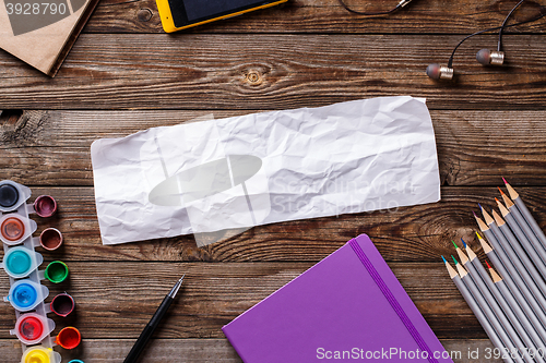Image of Watercolors, color pencils and sketchbook on wooden table. Flat lay photo with empty space for logo, text.