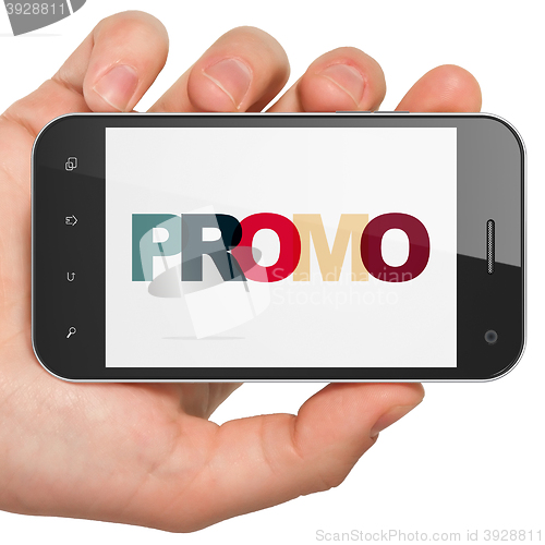 Image of Marketing concept: Hand Holding Smartphone with Promo on  display