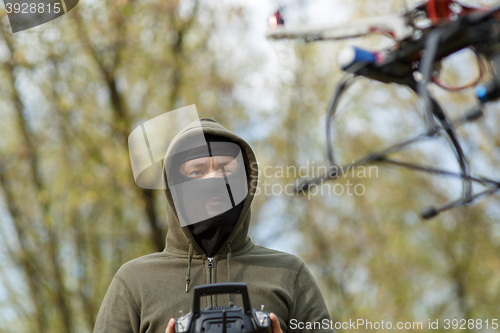 Image of Man in mask operating a drone with remote control.