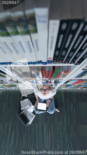 Image of female student study in library, using tablet and searching for 