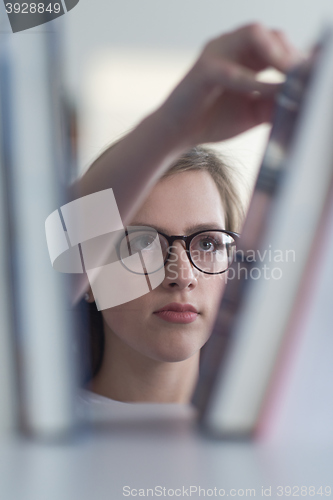 Image of portrait of famale student selecting book to read in library