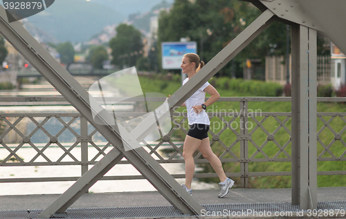 Image of sporty woman running  on sidewalk