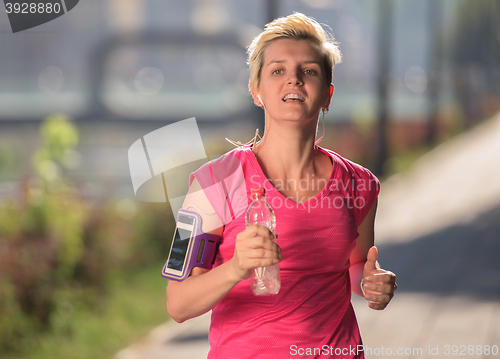 Image of sporty woman running  on sidewalk