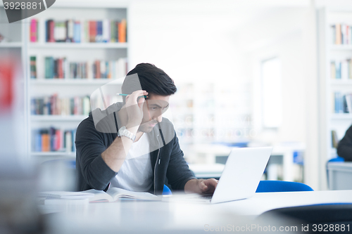 Image of student in school library using laptop for research