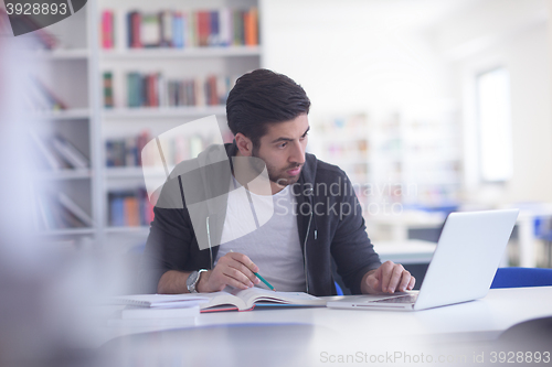 Image of student in school library using laptop for research