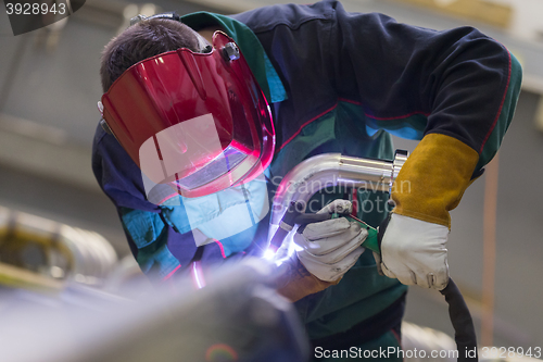 Image of Industrial worker welding in metal factory.