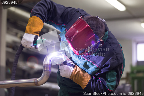 Image of Industrial worker welding in metal factory.