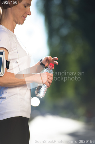 Image of woman drinking  water after  jogging