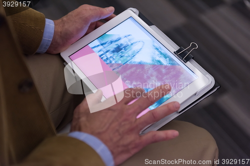 Image of Closeup of mature hands holding tablet.