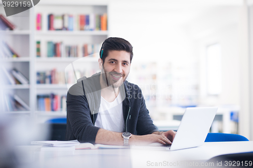 Image of student in school library using laptop for research